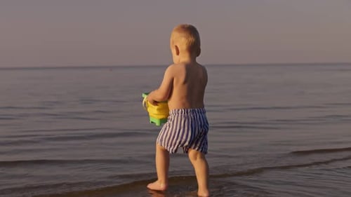 Child Playing with Bucket at the Beach at Sunset
