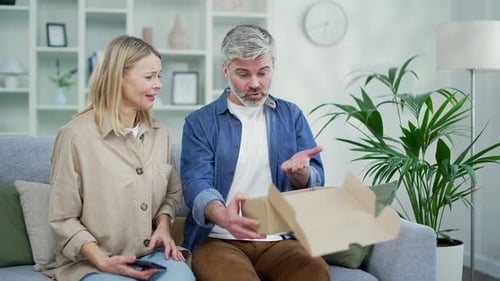Couple Opening Package While Woman Talks on Mobile