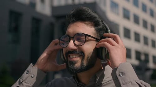 Happy Carefree Arabian Man Guy Wear Headphones Listen Loud Music Outdoors in Sunny City Enjoy High