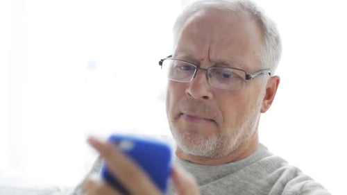 Senior man using smartphone at home, calling