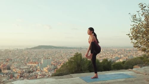Une fille fait du yoga debout sur une jambe au belvédère à l'aube