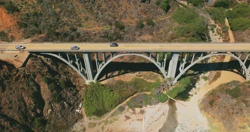 Seguindo os carros que se movem pela ponte em arco que liga montanhas na Califórnia