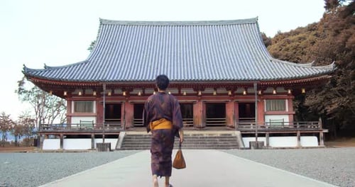 Guy wearing a Yukata walking towards a temple to go pray in Kyoto, Japan soft lighting