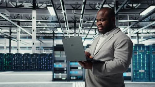 Computer Scientist Using Laptop in Data Center Managing Server Virtualization