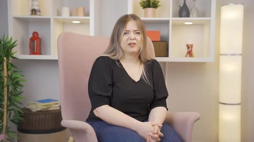 Worried Woman Sits in an Armchair Indoors