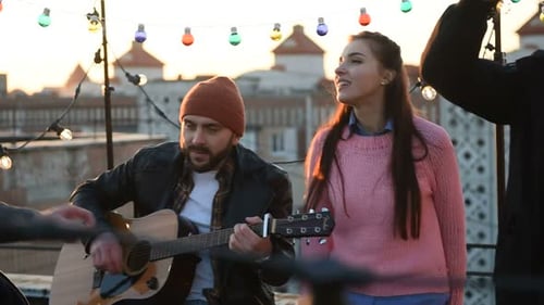 Young Adults Enjoying Music on Rooftop at Sunset