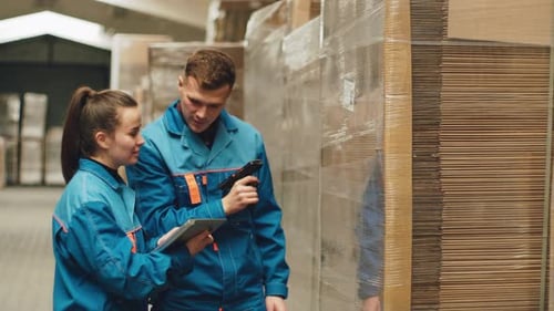 Warehouse Workers Using a QR Code Reader Scan the Barcode of the Goods