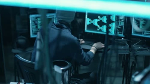 Vue arrière d'un hacker adolescent infectant par des virus les serveurs de données des infrastructures gouvernementales. Sa cachette