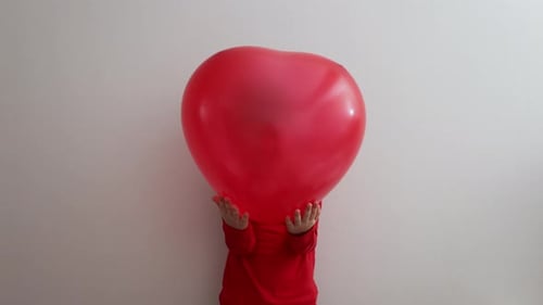 Child Hiding Behind a Red Heart Balloon
