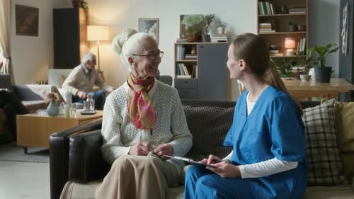 Elderly Woman Having Conversation with Female Caregiver in Nursing Home