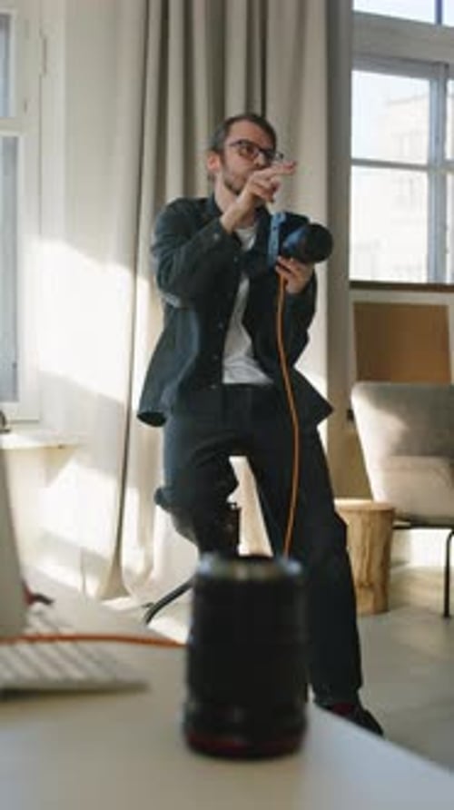 Adult Sitting With Camera Indoors