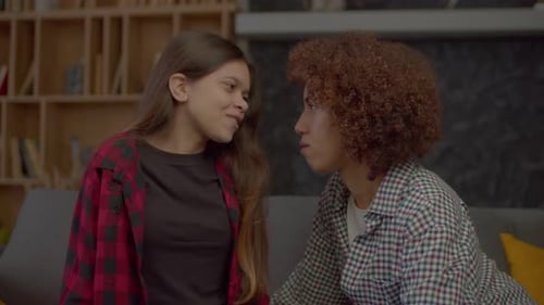Jolie adolescente multiethnique avec une mère afro-américaine partageant des secrets sur le canapé