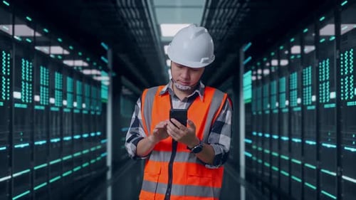 Asian Male Engineer Using Smartphone in Data Center