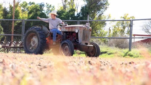 Young Adult Driving Tractor in a Rural Field