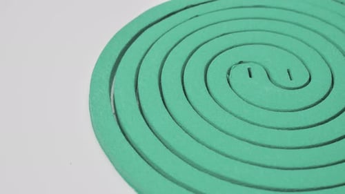 Spirale à moustiques tournant sur un moulinet sur fond blanc