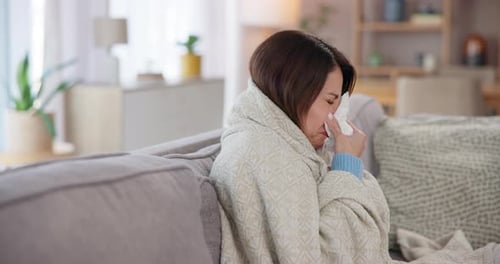 Woman Wrapped in Blanket Using Tissue on Couch