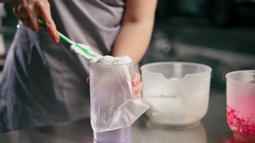 Nahaufnahme: Bäckerin in professioneller Küche füllt Sahnepaste in einen Spritzbeutel