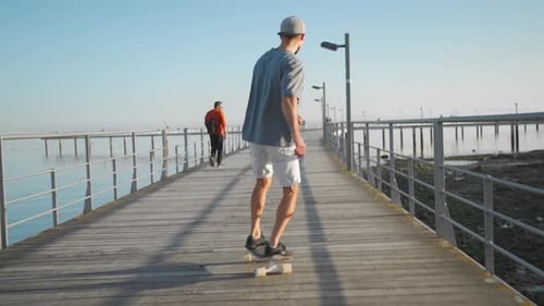 Man Ride Skateboard on Bridge Near Ocean