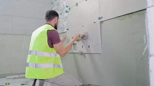 Man Tiling Wall in Unfinished Bathroom