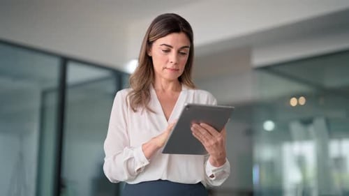 Middle Aged Busy Business Woman Using Digital Tablet Standing in Office