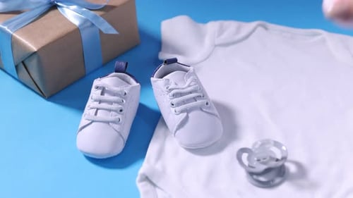 Baby shower. Woman putting toy onto light blue background, closeup