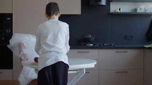 Schoolboy Preparing School Supplies at Kitchen Table at Home