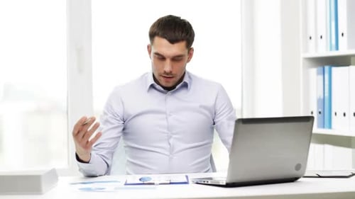 Focused Man Analyzes Business Reports in Office