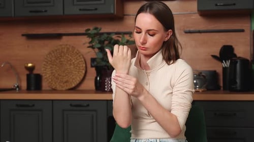 Young Woman Massages Sore Wrist Indoors