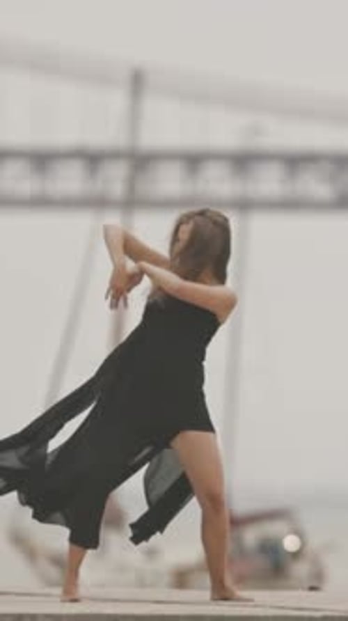 A Woman in Black Dress Dancing on the Pier in