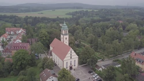 Church in a small German village surrounded by the forest, aerial footage in 4k