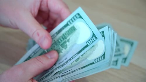 As mãos dos homens contam dólares.