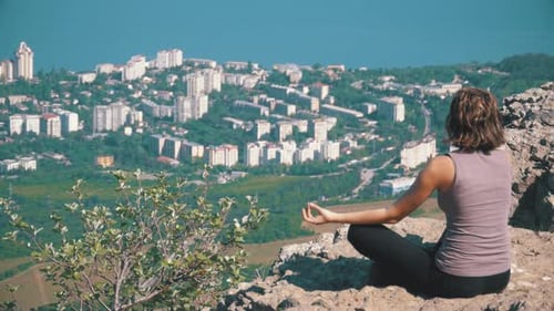 Sitting Woman in Lotus Position Practicing Yoga Moves Cliff Top with the Cross