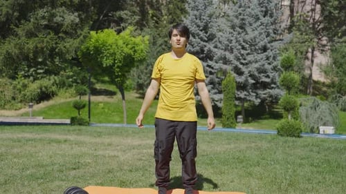 Young man exercising in the park doing body stretches with his arms.