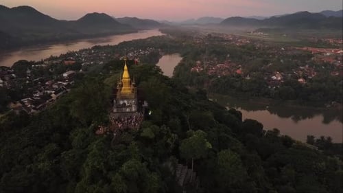 Drone statique encadrant un temple isolé au sommet d'une ancienne ville entourée d'une rivière paisible, d'un mont