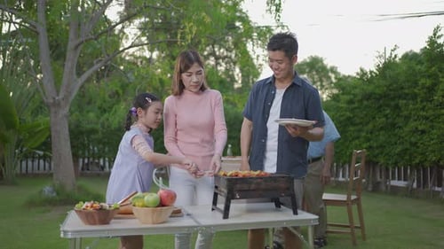 Family Enjoys Backyard Barbecue Together on Summer Day