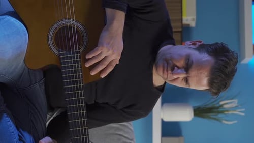 Man Plays Acoustic Guitar In Home Setting