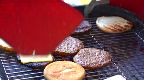 Blowing grill and turning meat patty. Close up of grill with burgers