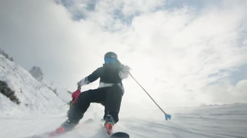 niedriger Winkel eines männlichen Skifahrers, der eine leichte Skipiste hinuntergeht