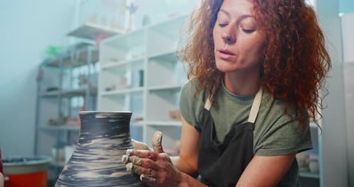 Female Potter Shaping Clay on Wheel in Studio