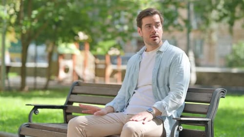 Waiting Casual Young Man Checking Time while Sitting in Park