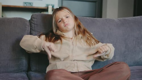 Unhappy Girl Sitting on Couch Gives Thumbs Down