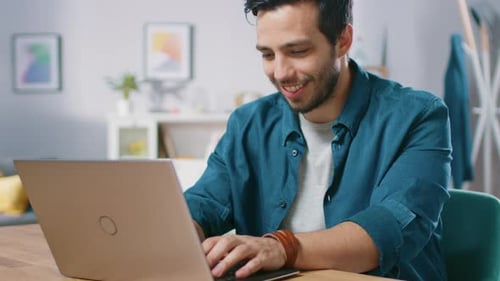 Man Typing on Laptop at Wooden Desk Indoors