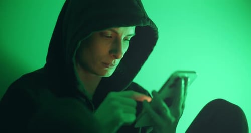 Adult in Hooded Top Using Mobile Phone