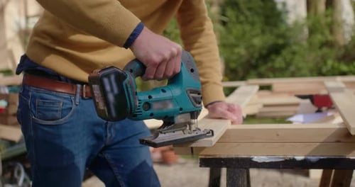 Person Cutting Wood Board with Power Saw