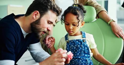Dentist Explains Teeth Model to Child Patient