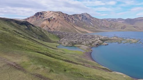Direct smooth drone approach to lava field in Frostastaðavatn lake. Rhyolite mountains in the backgr