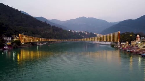 pont suspendu en fer illuminé par des feux de ferry avec vue sur les rives du Gange le soir, vue aérienne