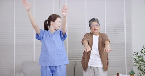Young Woman Assists Senior with Arm Exercises at Home