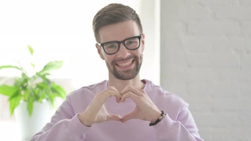Young Adult Makes Heart With Hands, Smiling