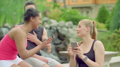 Cheerful Friends Having Fun In Park. Young People Using Phone Outdoor At Summer. Happy Friends La...